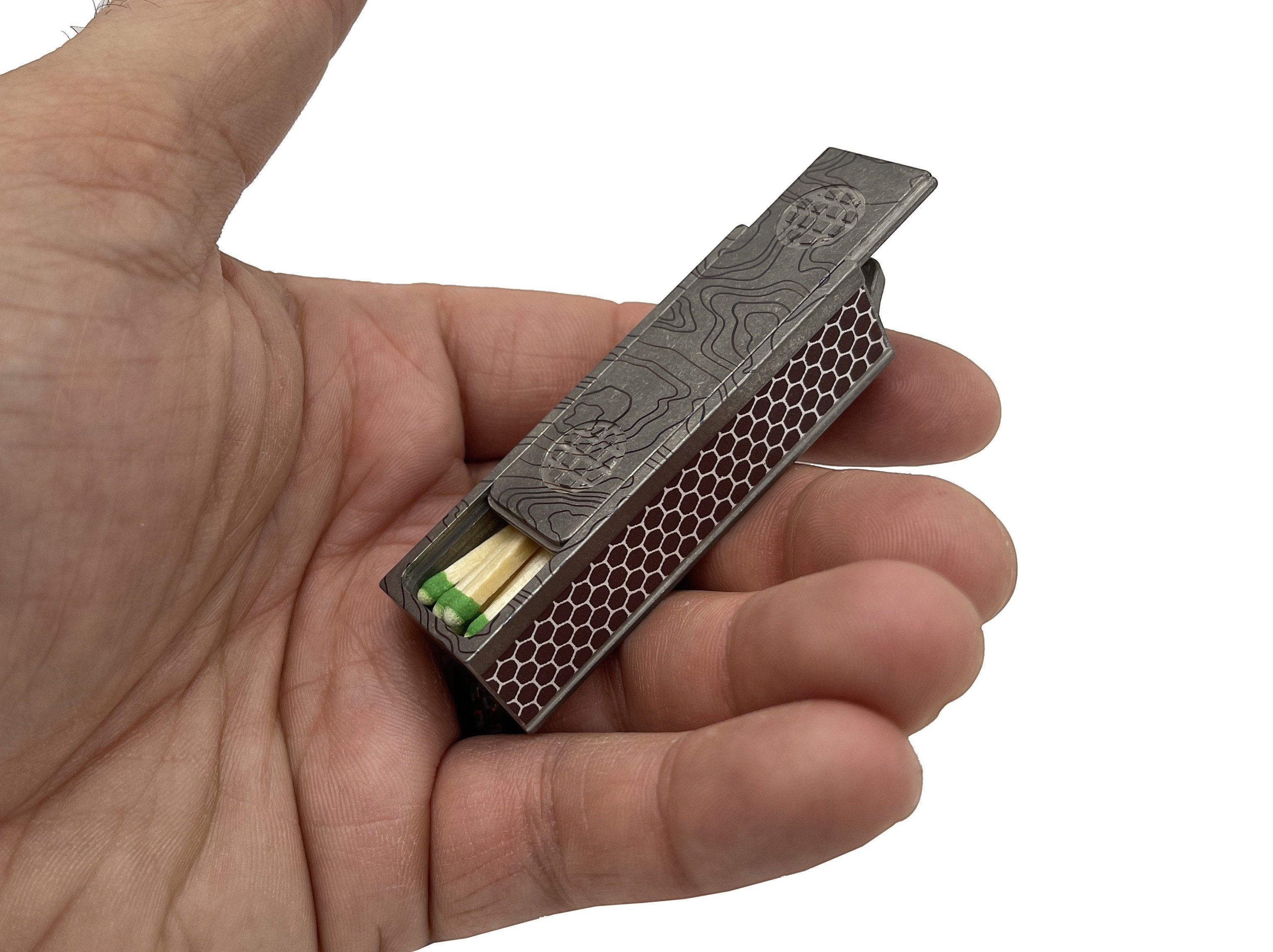 CountyComm Titanium Match Slide Box with topographical map pattern, loop, and strike pads. Holds matches or pills.