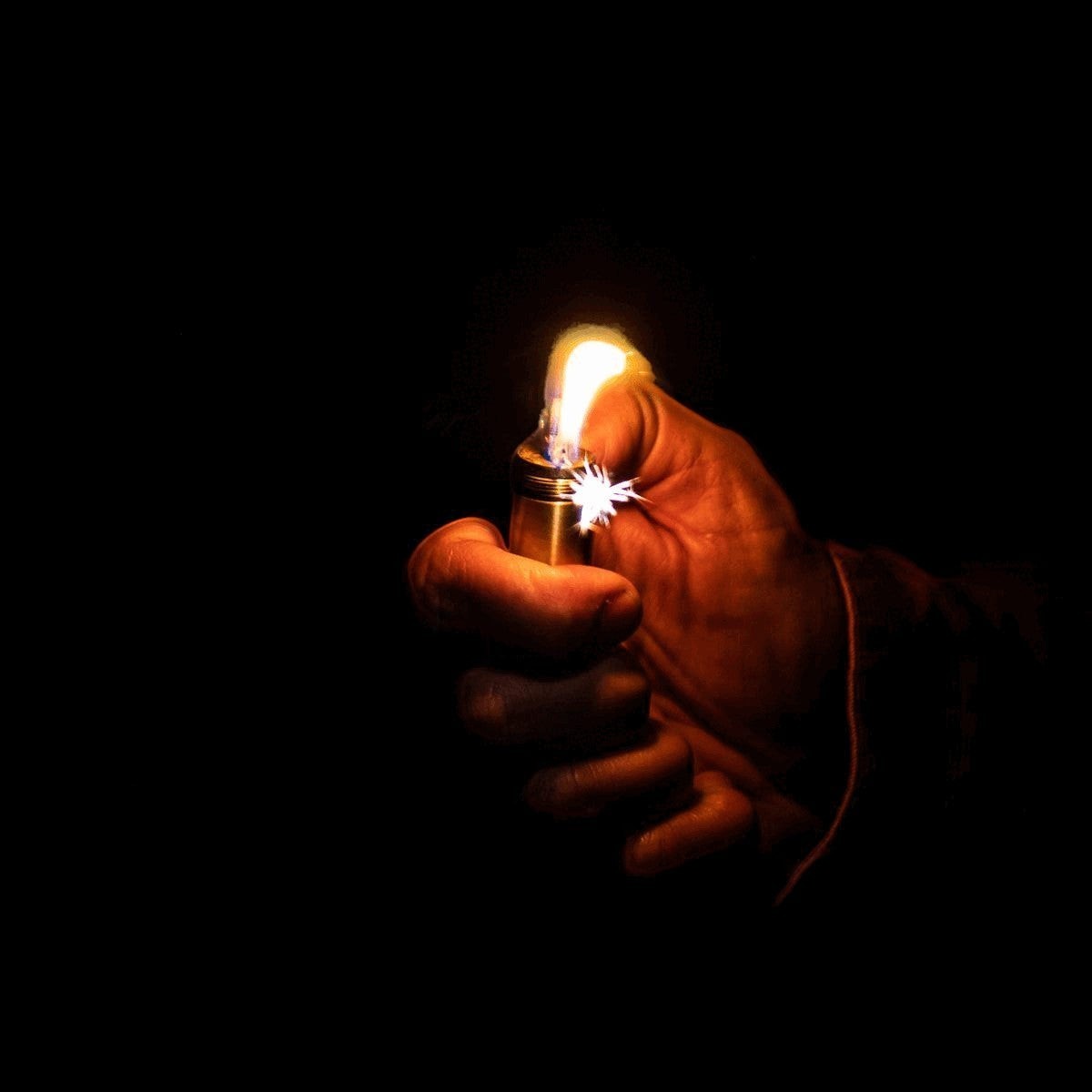 CountyComm Brass XL Peanut Lighter Gen 4 TOPO with full topo engraved body, lit in hand.
